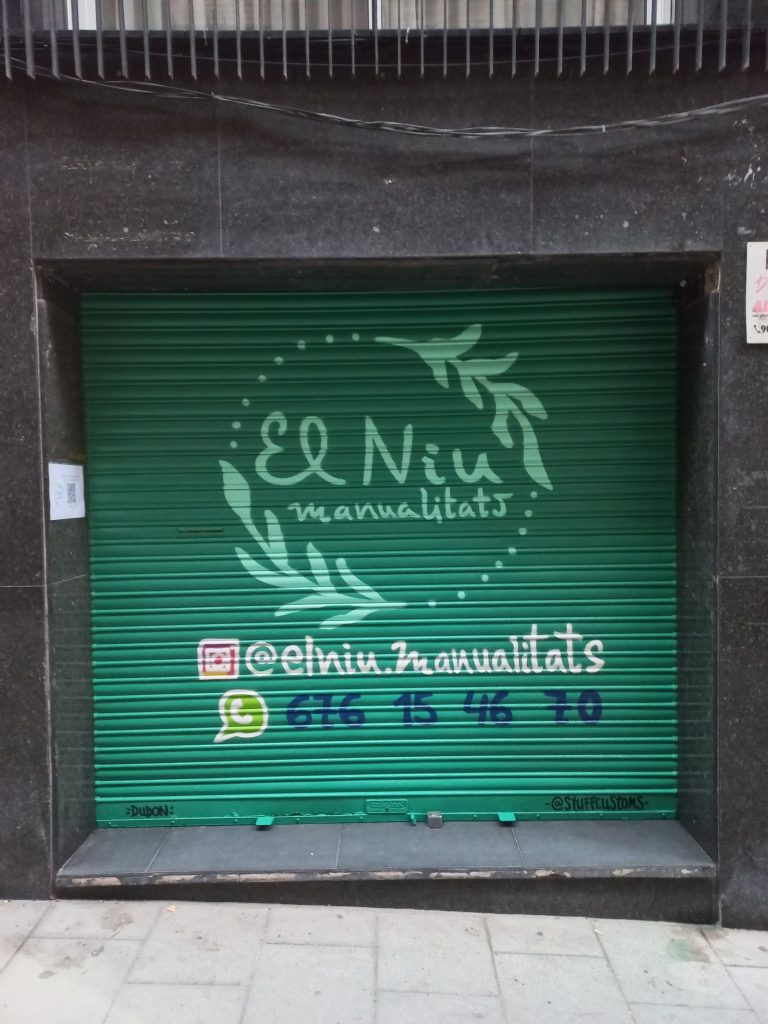Graffiti con logotipo en persiana estándar de taller de manualidades en Satn Gervasi, Barcelona
