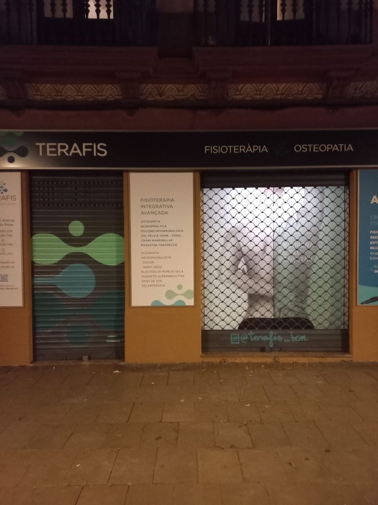 Graffiti en persiana con agujeros de comercio fisioterapia deportiva en Poble Sec, Barcelona