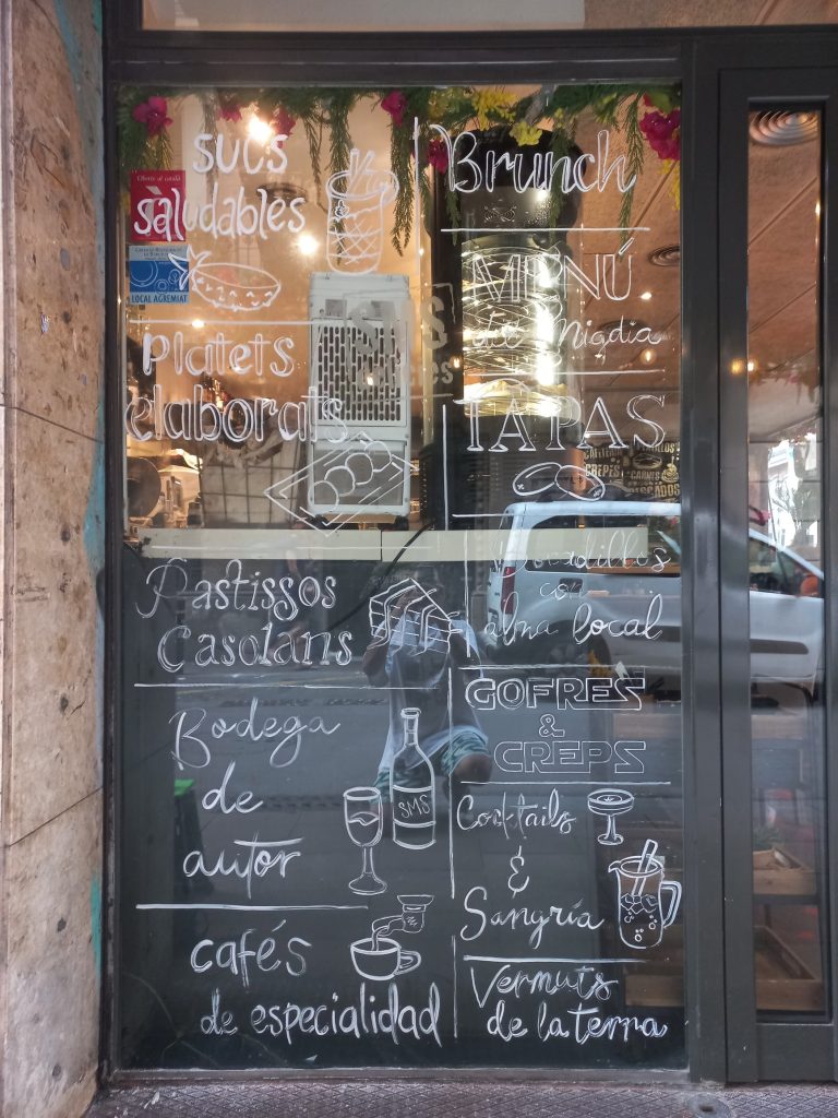 Proceso de creación de rótulos pintados a mano alzada en los cristales de un local de brunch en el Barrio de Gràcia, Barcelona.