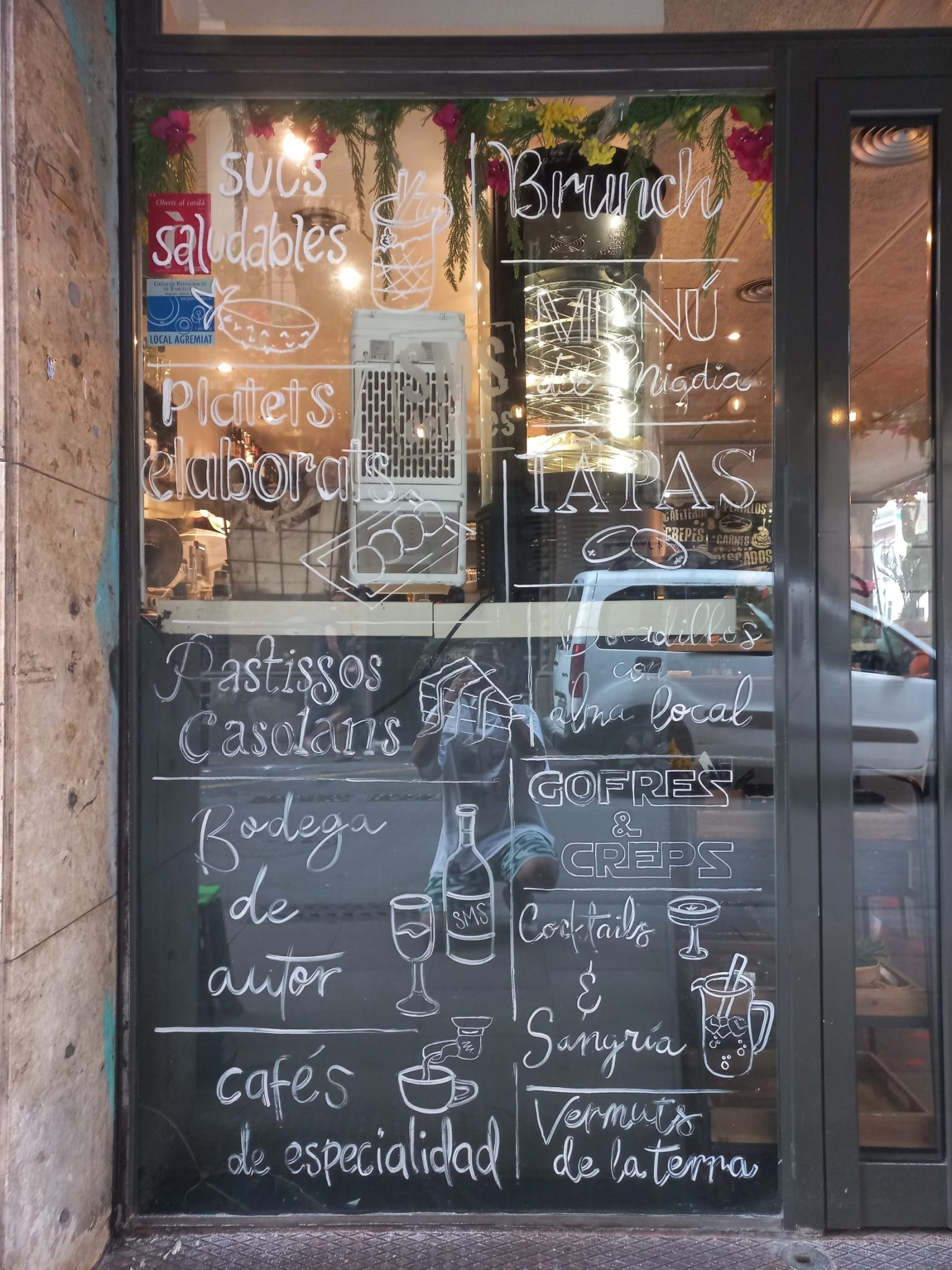 Proceso de creación de rótulos pintados a mano alzada en los cristales de un local de brunch en el Barrio de Gràcia, Barcelona.