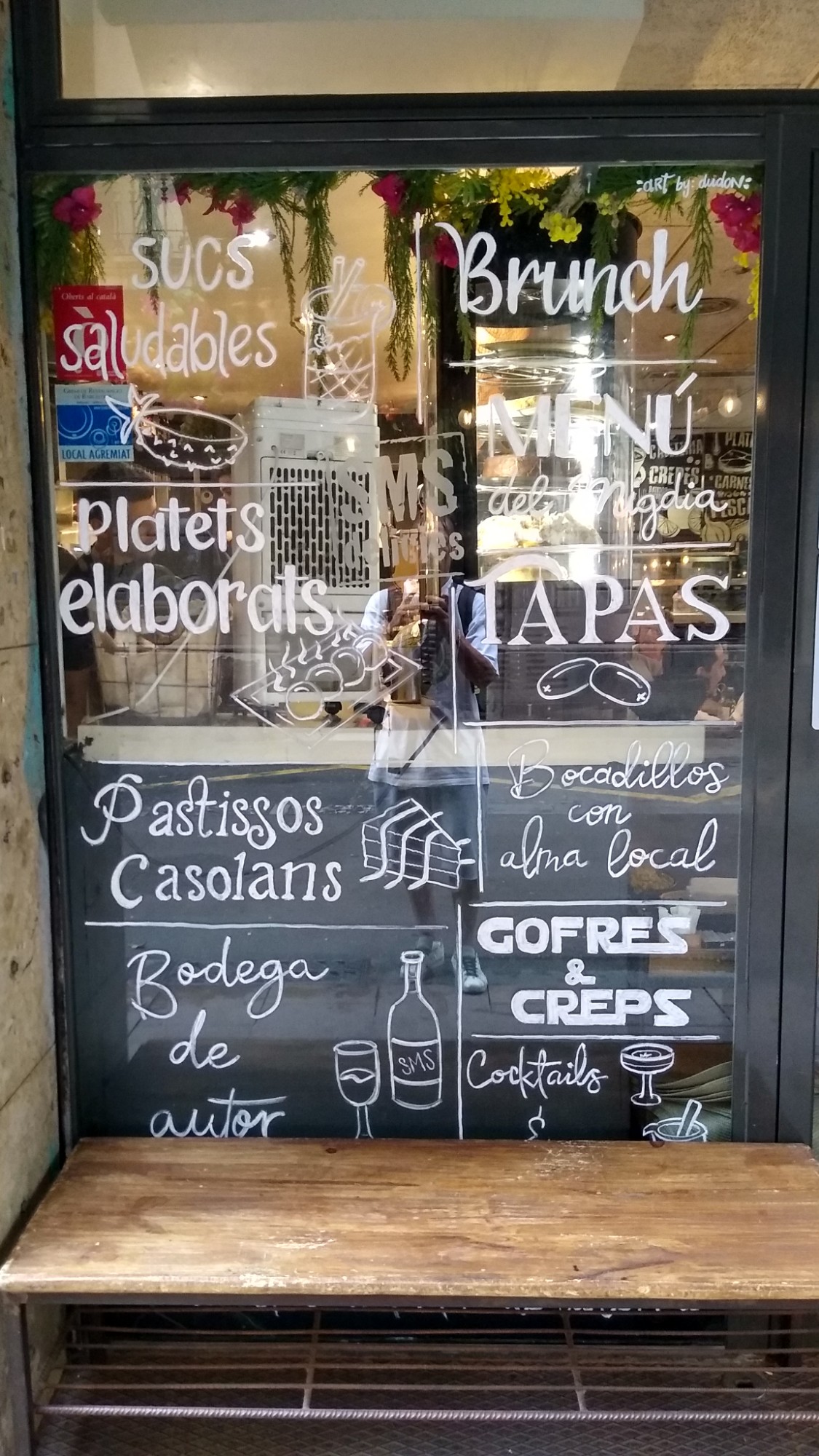 Escaparate de cafetería de brunch en el barrio de Gràcia con rotulación manual artística, técnica de pintura sobre vidrio.