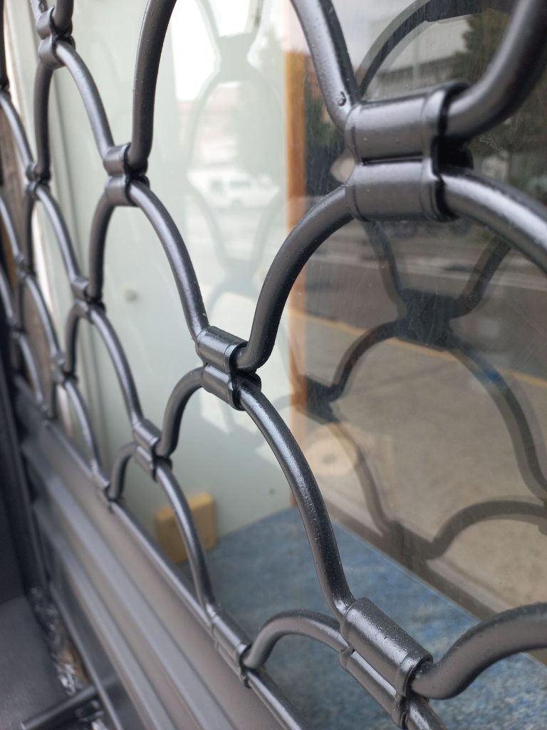 Detalle de pintura técnica en rejas metálicas negras (plano cercano)