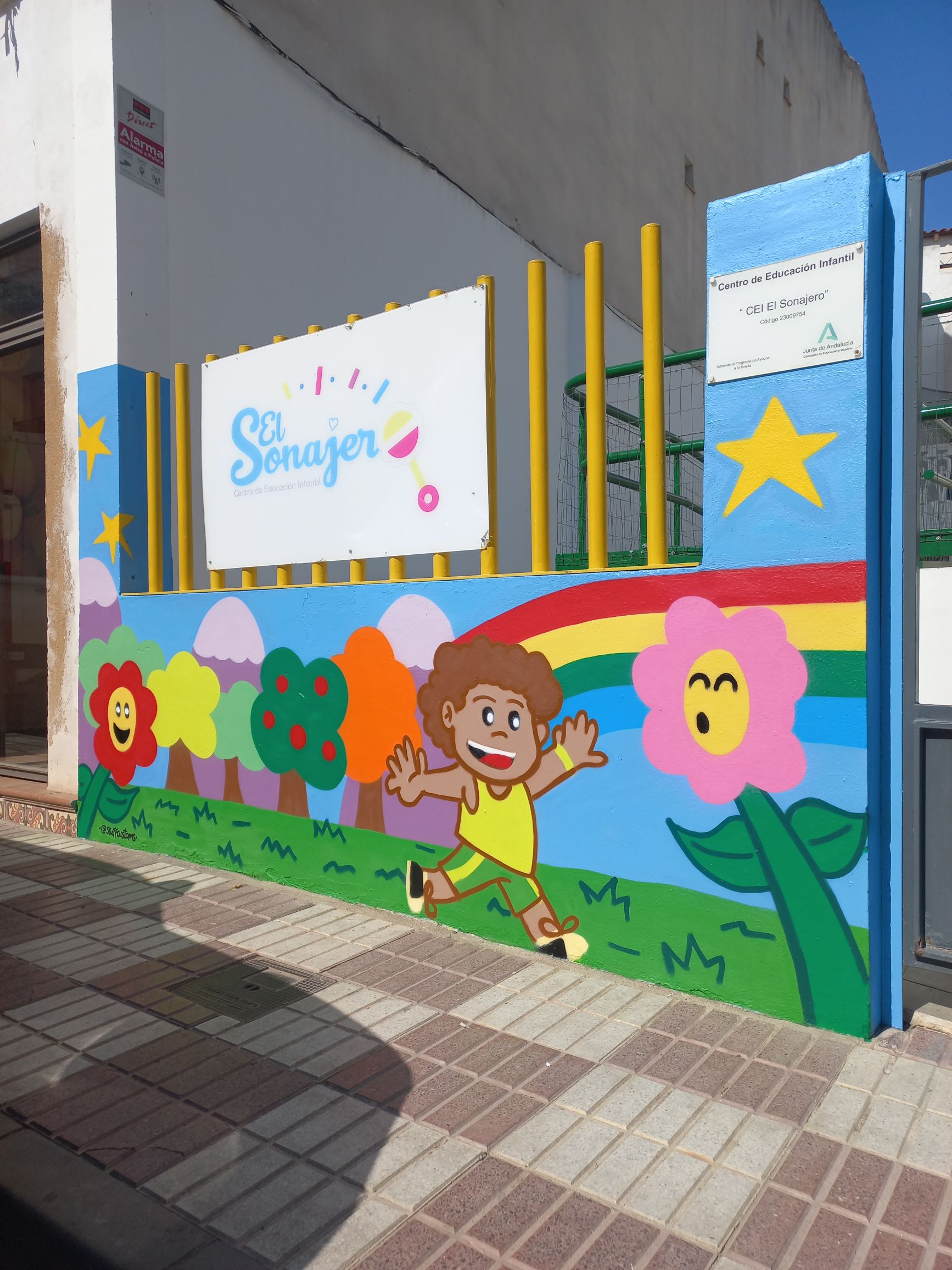 Fachada de guardería en Jódar (Jaén) totalmente decorada con graffiti profesional de estilo infantil, mural colorido con personajes realizado por stuffcustoms.