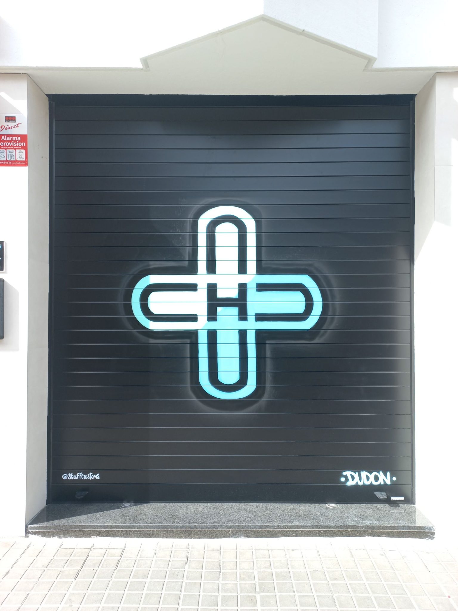 Detalle de graffiti limpio y profesional en persiana lateral de farmacia, uso de colores corporativos verdes y blancos por stuffcustoms