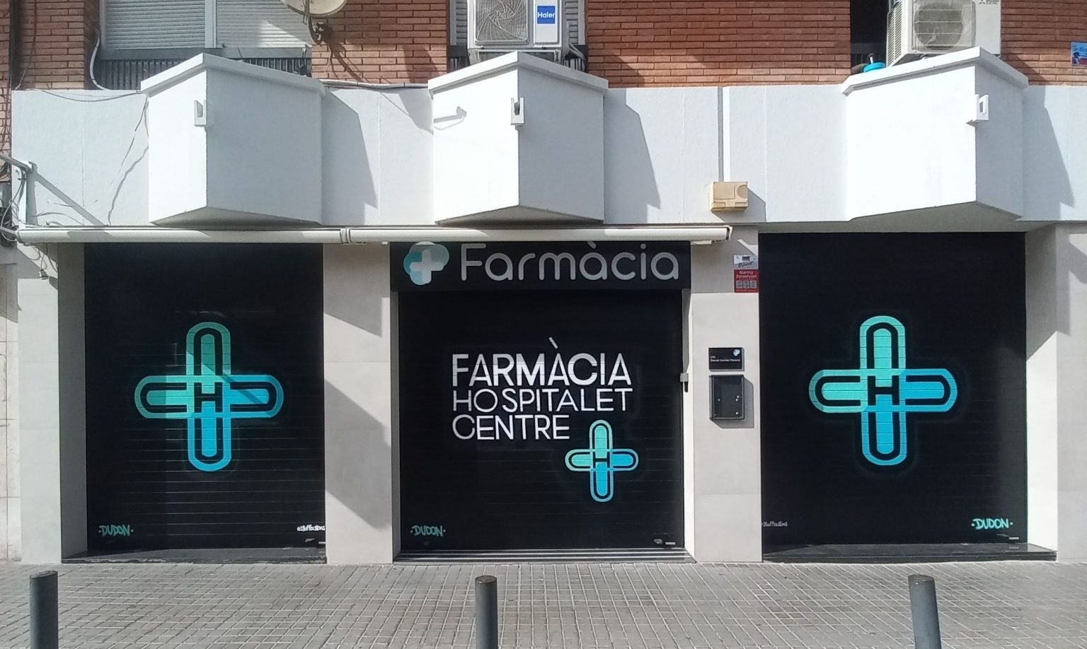Conjunto de tres persianas metálicas pintadas con graffiti profesional para una farmacia en Hospitalet de Llobregat, diseño unificado y corporativo por stuffcustoms.