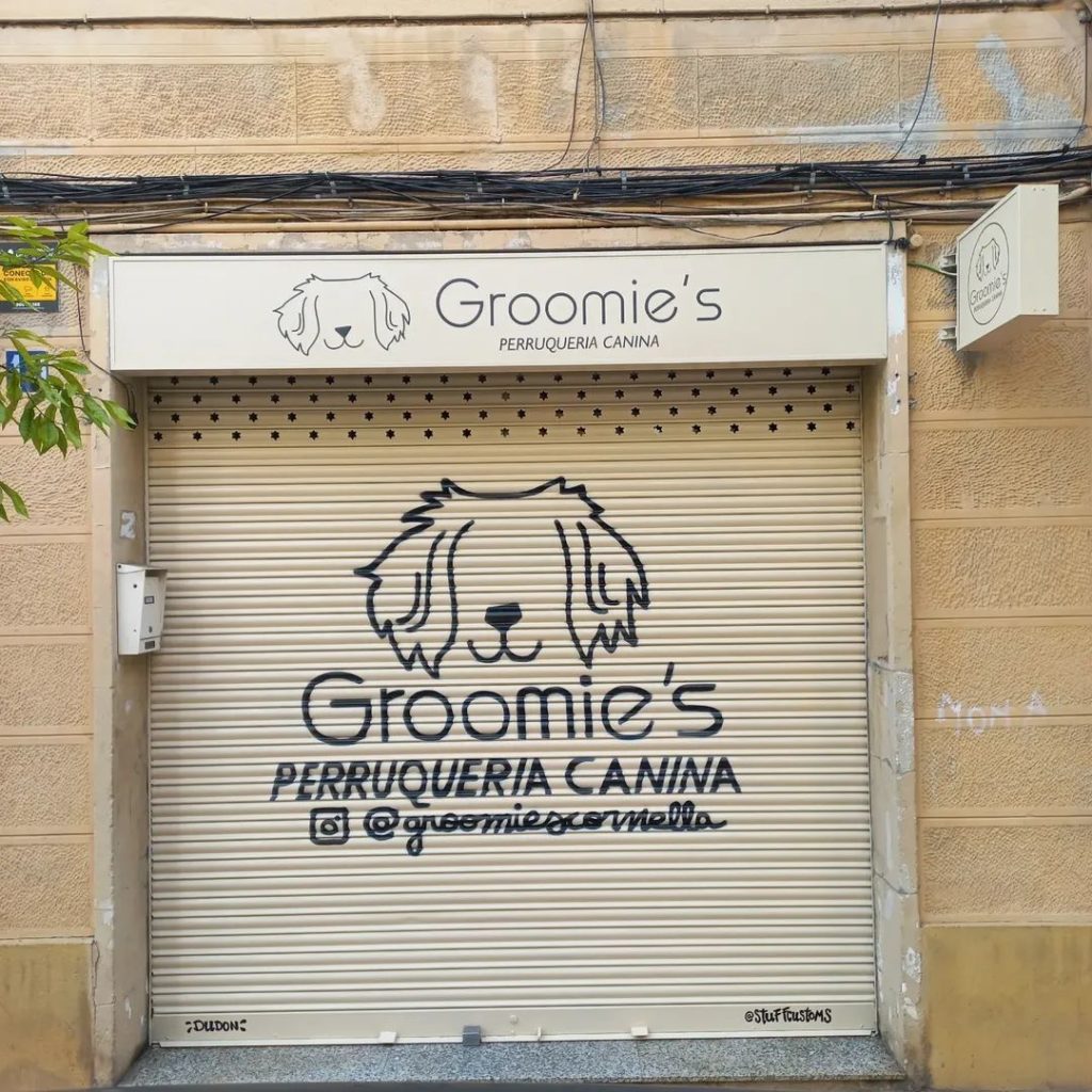 Graffiti de logotipo para la peluquería canina Groomies en Cornellà de Llobregat, pintado a mano sobre persiana metálica de negocio.